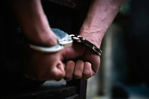 Man on the chair in Handcuffs. Rear view and Closeup ,Men criminal in handcuffs arrested for crimes. With hands in back,boy prison shackle in the jail violence concept.